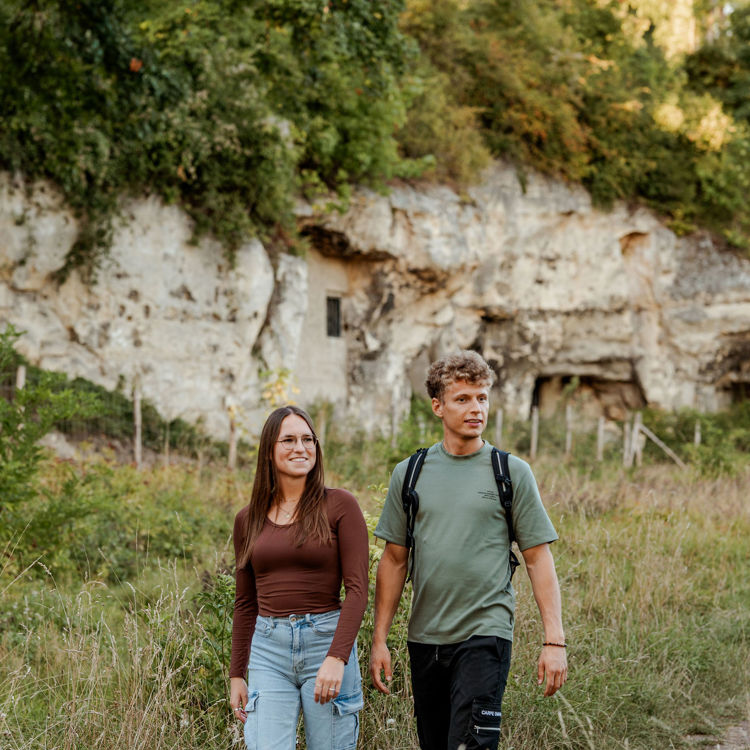 Jong koppel loopt met een mergelwand op de achtergrond. 
