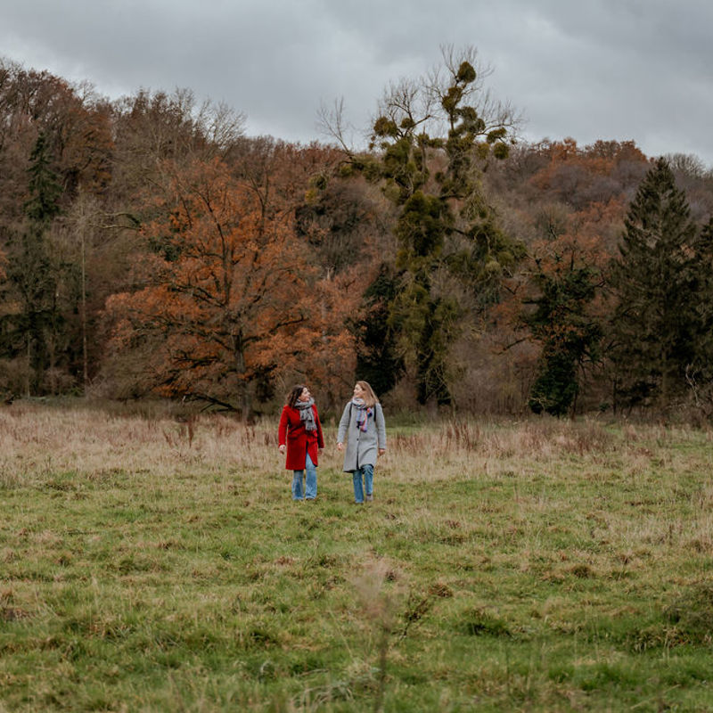 Twee wandelaars in natuurgebied Ingendael met het bos op de achtergrond. 