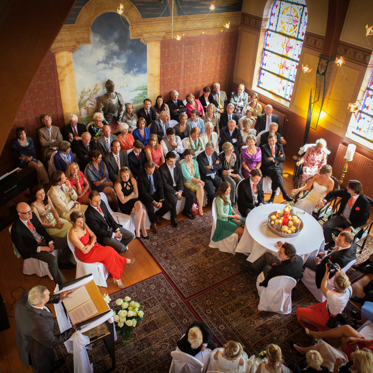 Huwelijk dat plaatsvindt in een sfeervolle ruimte in een kasteel gevuld met bruiloftsgasten.