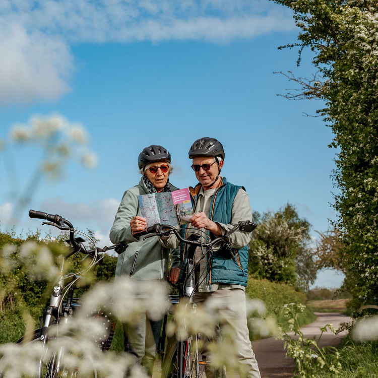 Echtpaar bekijkt routeboekje tijdens een fietstocht langs bloesem.