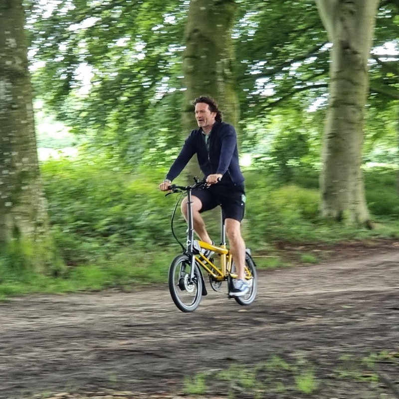 Sander fiets op een elektrische vouwfiets door het bos. 