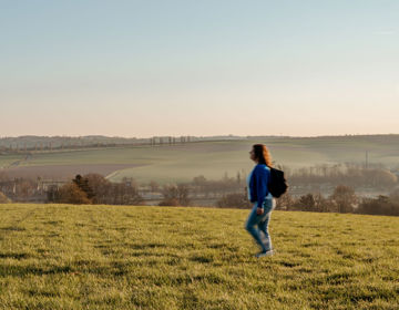 Meisje met rugzak wandelt alleen op panoramaplek in zuid-limburg.
