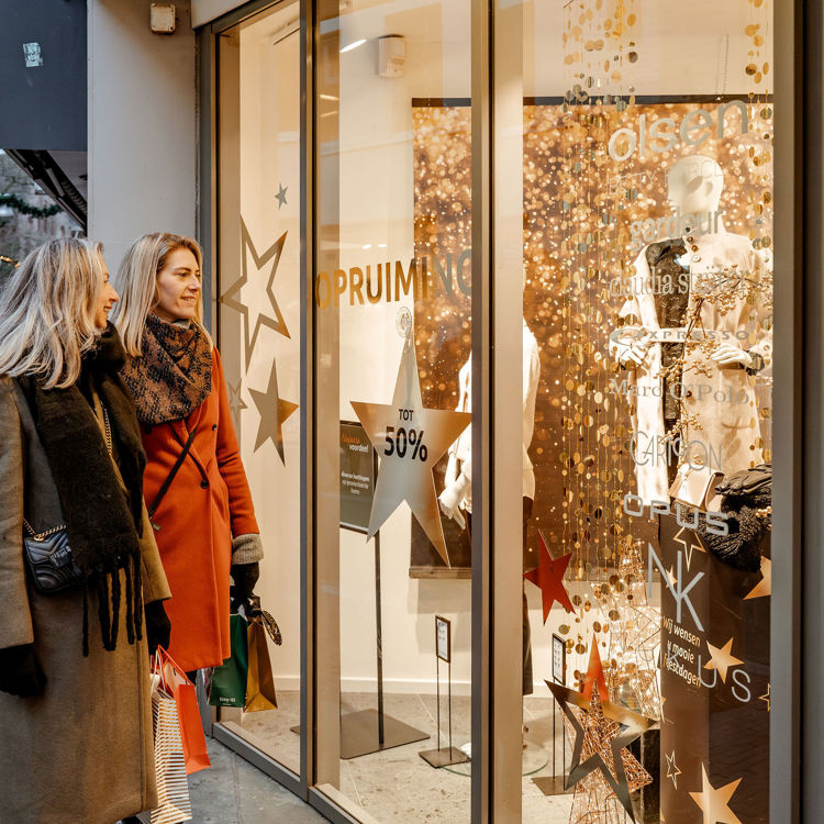 Twee vriendinnen kijken naar etalage tijdens de kerstperiode. 