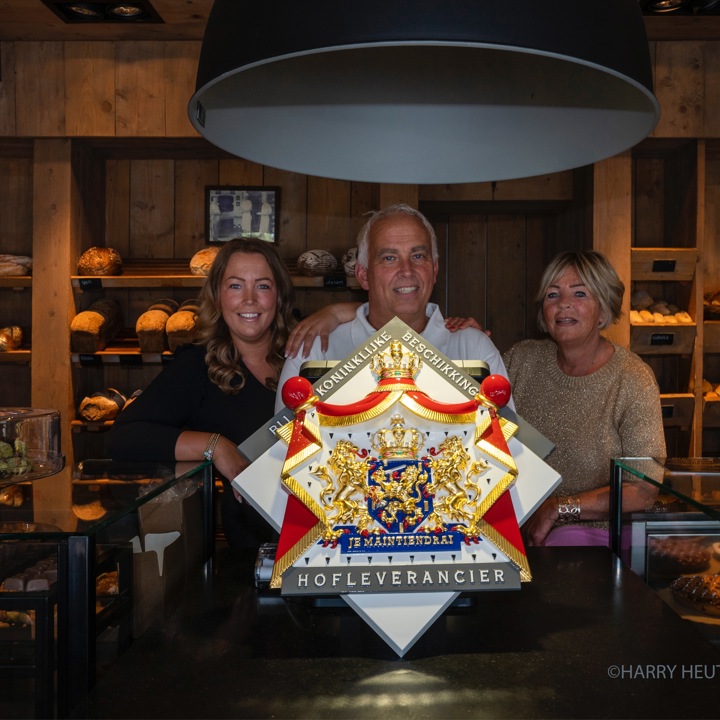 Eigenaren van bakkerij poseren met een koninklijke oorkonde in de bakkerij. 