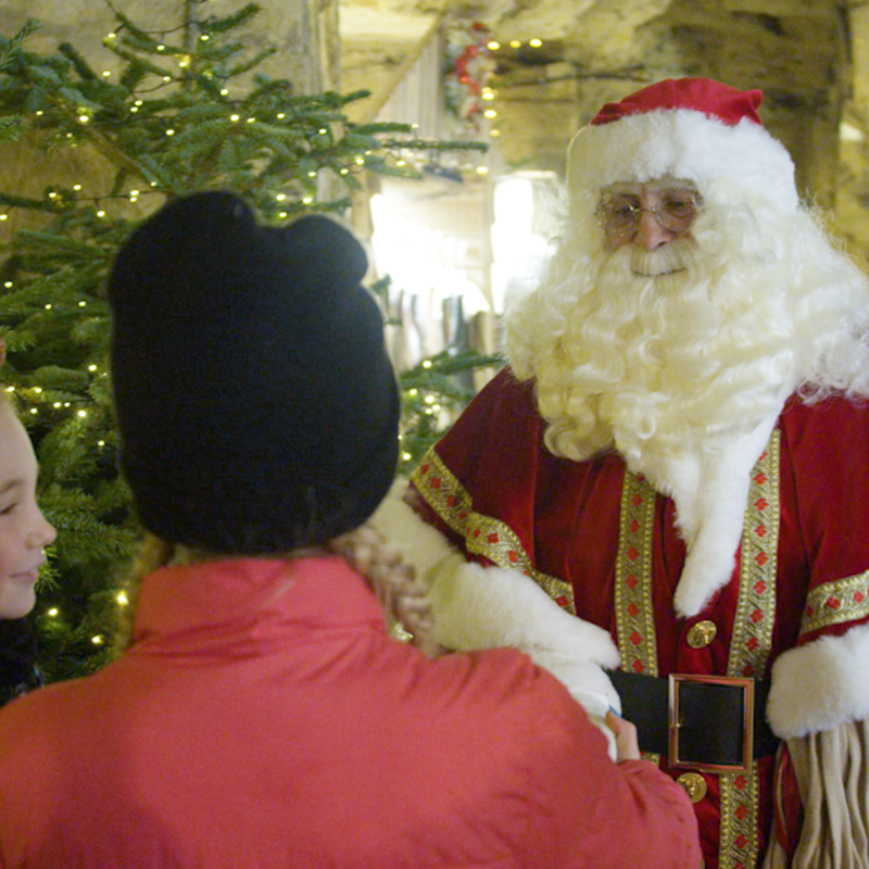 vrouw en meisje in gesprek met kerstman in grot
