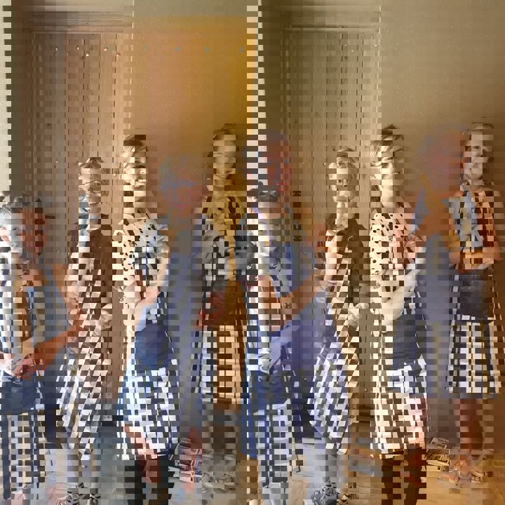 Presentatrice en 3 kinderen in blauw-wit geblokje kookschorten houden ieder een deegroller vast