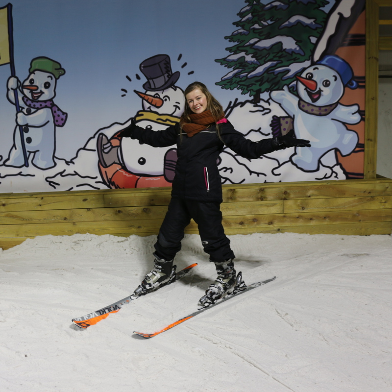 Jonge vrouw op ski's bovenaan de piste bij Snowworld