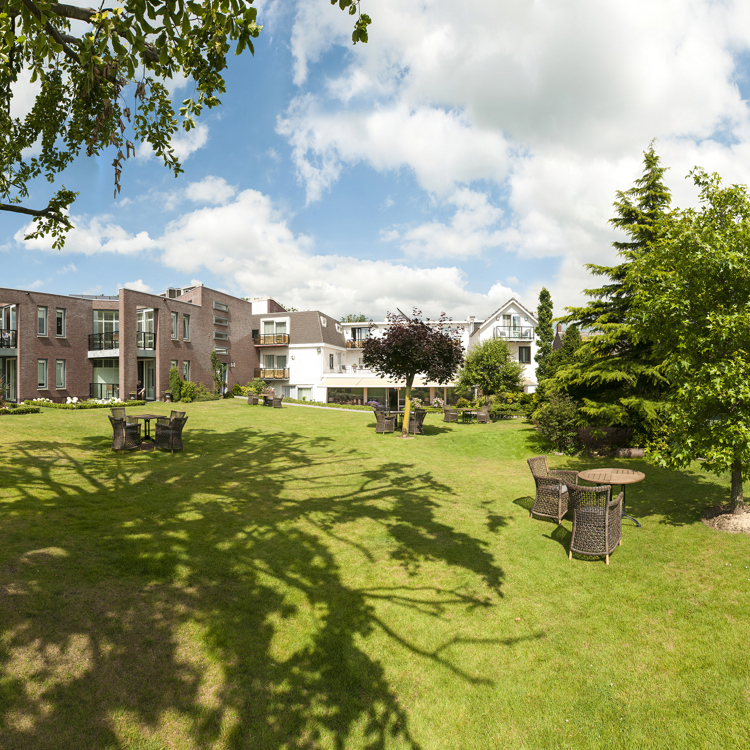 Grasveld in een tuin met in de verte een gebouw.