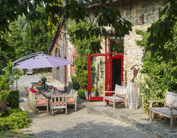 opgeknapte boerderij met openslaande deuren en een groot terras met parasol. 