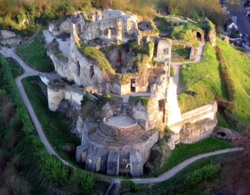 Een ruïne bekeken vanuit vogelperspectief met daaromheen een wandelpad naar boven. 