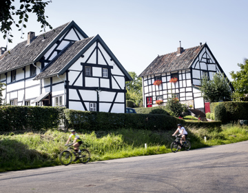 Fietsers fietsen langs vakwerkhuizen