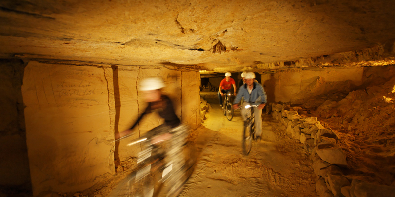 Mensen mountainbiken in de grotten van Valkenburg