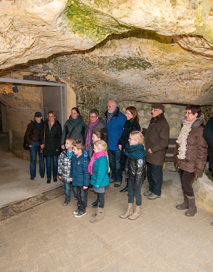 Gids geeft rondleiding aan grote groep mensen bij de Fluweelengrot Valkenburg