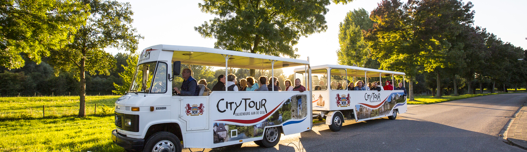 Treintje van Citytours rijdt over weg naast weiland op een zonnige dag