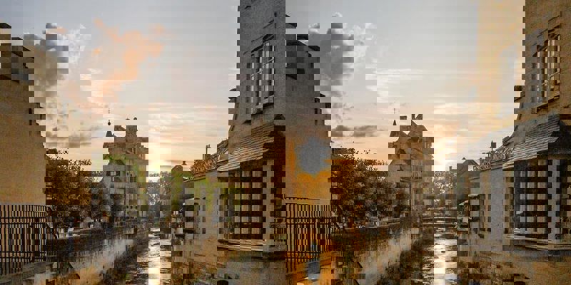 Beeld van Valkenburg met ondergaande zon vanaf met bloemen versierde brug richting Geulpoort