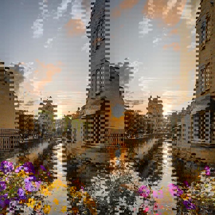 Beeld van Valkenburg met ondergaande zon vanaf met bloemen versierde brug richting Geulpoort