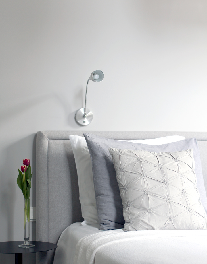 Detailfoto van een bed met grijs hoofdbord en 3 hoofdkussens