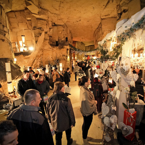 Mensen lopen langs kerstkraampjes in de Gemeentegrot in Valkenburg