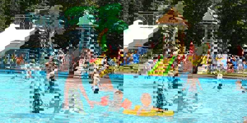 Volwassenen en kinderen hebben plezier in het buitenbad in de zomer bij het Steinerbos