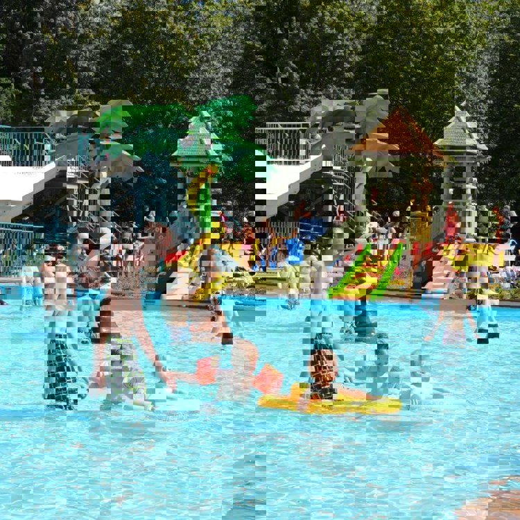 Volwassenen en kinderen hebben plezier in het buitenbad in de zomer bij het Steinerbos