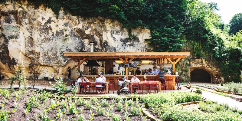 Mensen zitten op het terras bij de buitenkeuken Heerdeberg met op de voorgrond een groentetuin