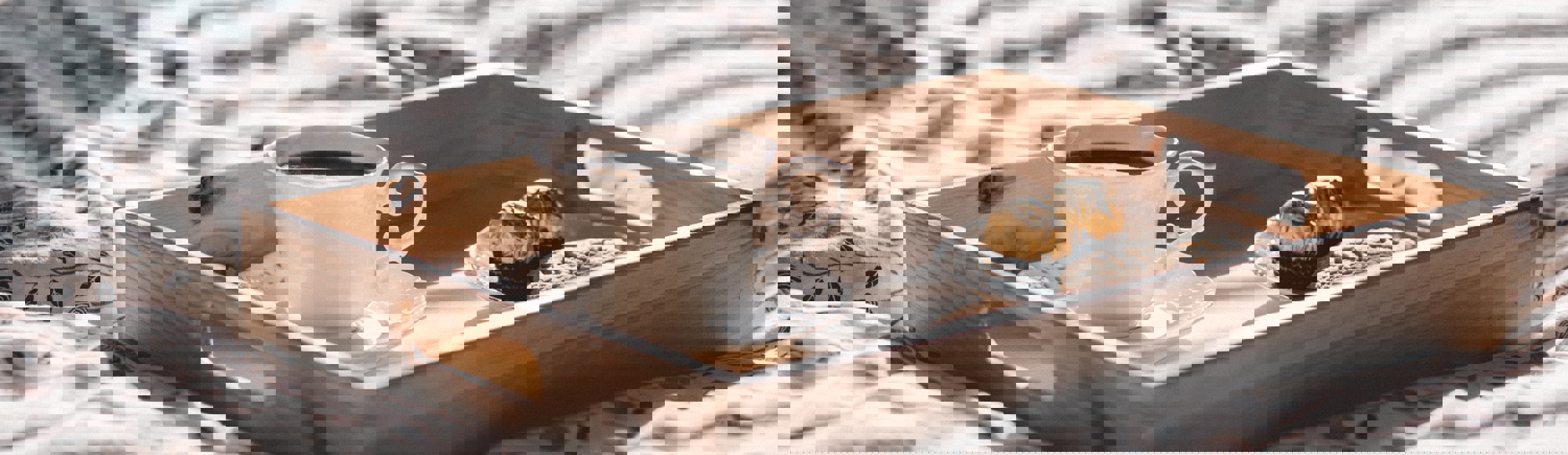 houten dienblad met koffie en bonbons op een hotelbed. 