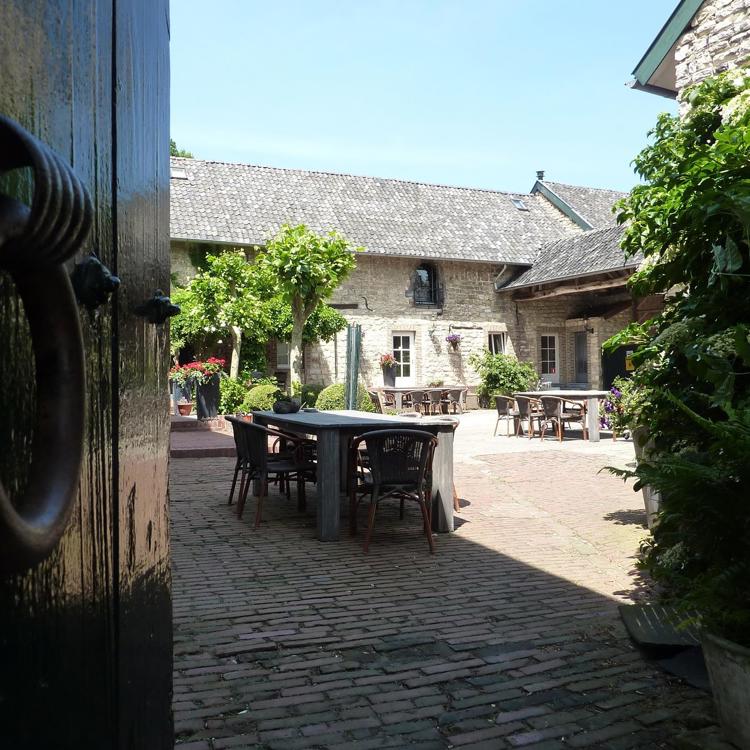 doorkijkje langs een deur richting de binnenplaats met terrassen. 