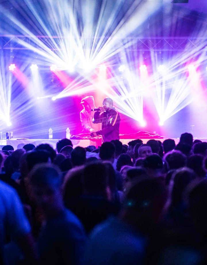 Rappers op podium met lichtshow geven optreden voor groot publiek