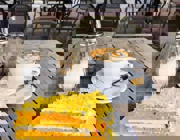 Een stuk carrot cake en kopje koffie geserveerd op het terras