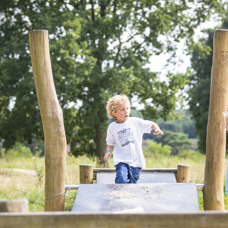 Kinderen spelen in een buitenspeeltuin in de natuur