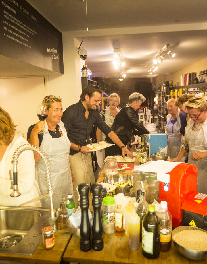 Een groep mensen is druk bezig in de keuken tijdens een kookworkshop
