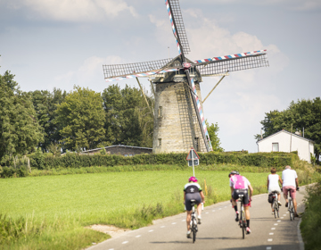 Wielrenners en gewone fietsers fietsen langs de Van Tienhovenmolen 
