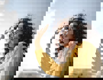 Zwaaiende vrouw met een gele blouse