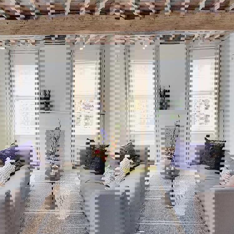 Interieur met twee banken in lichte kleuren en een houten plafond. 