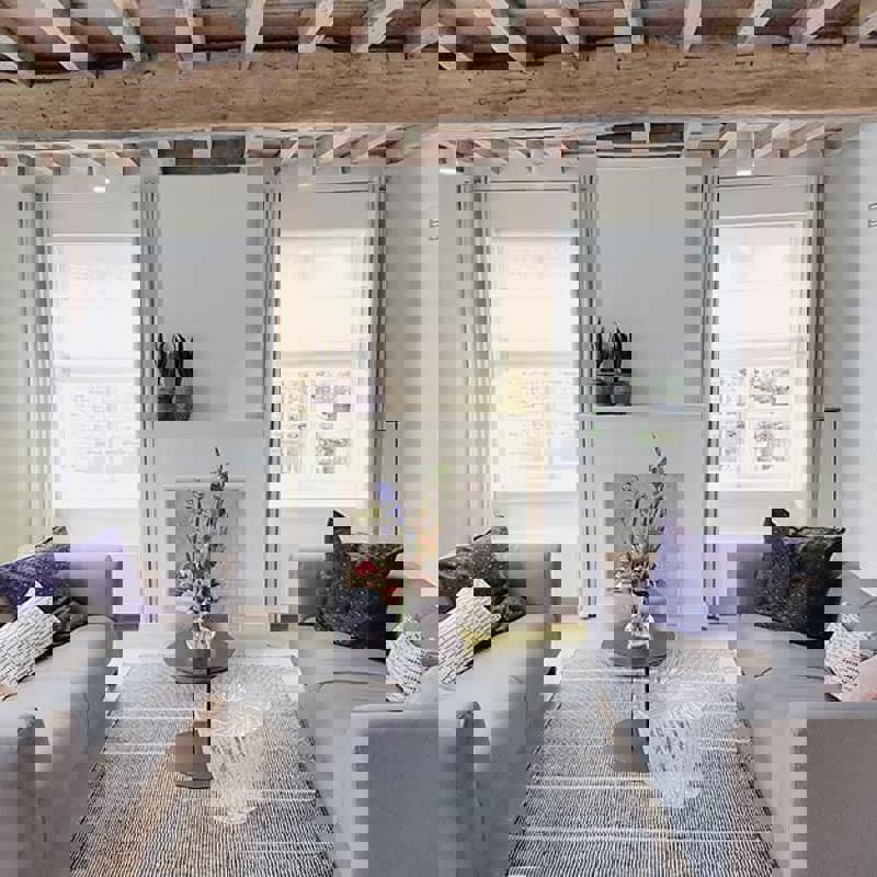 Interieur met twee banken in lichte kleuren en een houten plafond. 