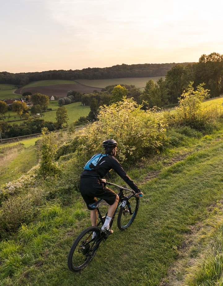 Mountainbiker fietst bergje op met zonsopkomst