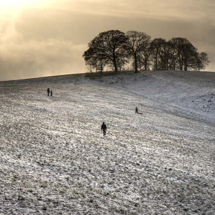 Uitgestrekte heuvels met een laagje sneeuw en een paar wandelaars