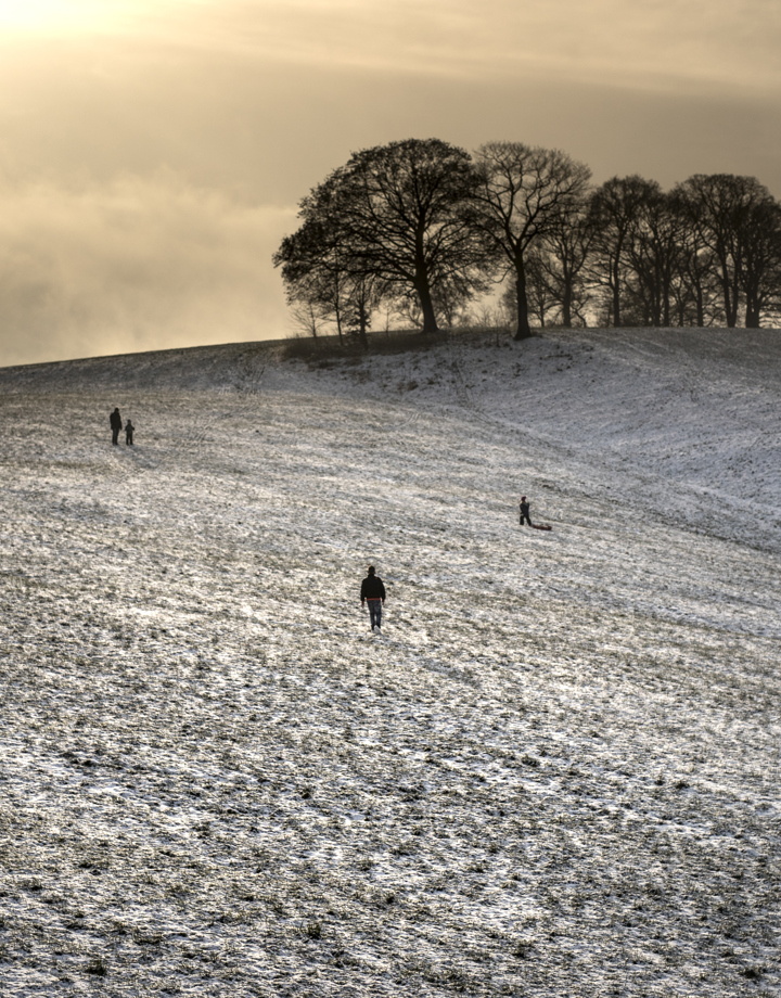 Uitgestrekte heuvels met een laagje sneeuw en een paar wandelaars
