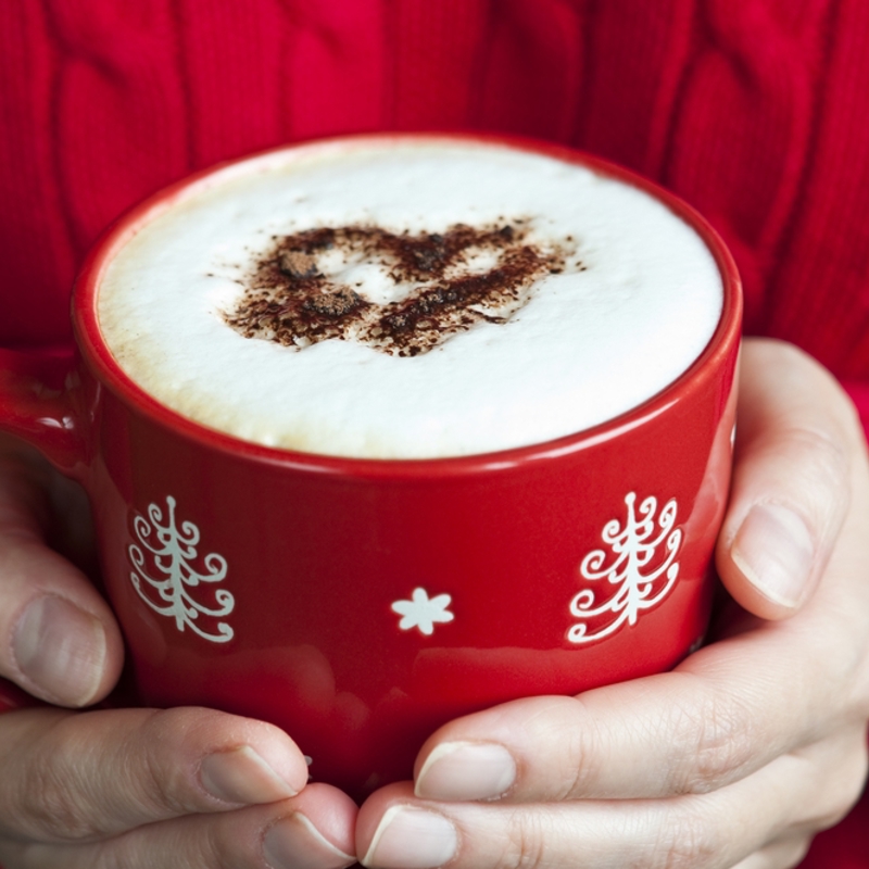 Close up iemand met rode trui en handen die rode mok met chocomel vasthouden