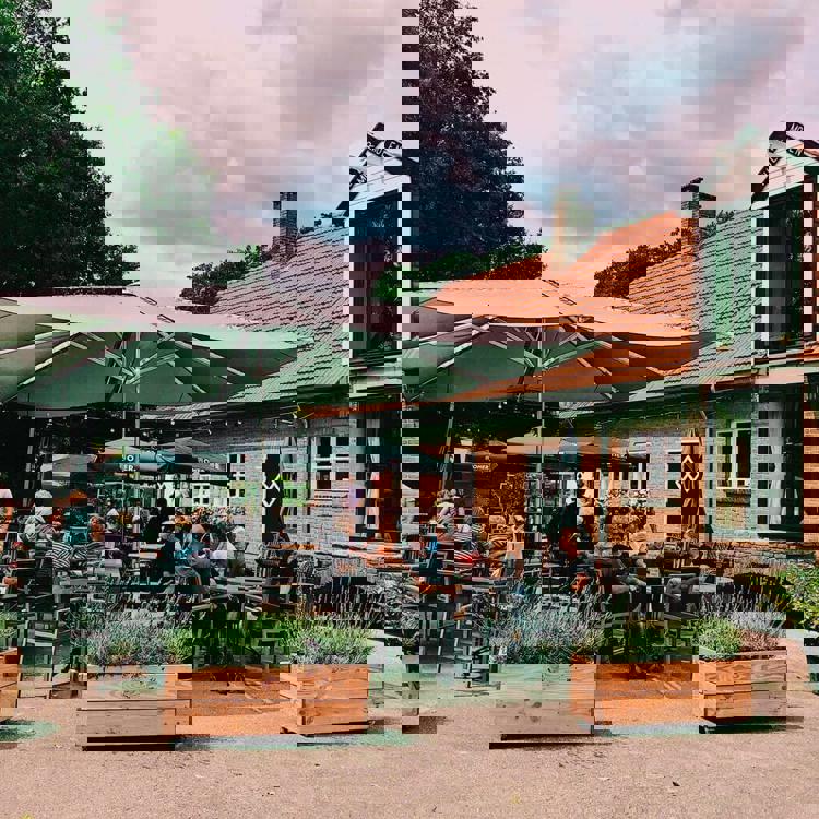 Mensen op terras onder parasol bij Muldermolen