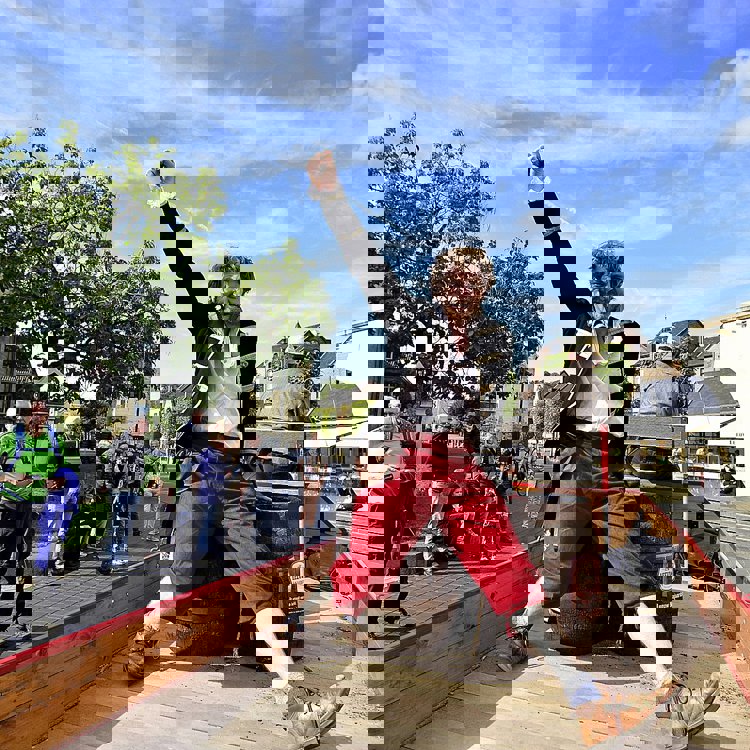 Man in Middeleeuws kostuum zittend op houten vaten houdt vuist in de lucht op kar in Centrum Valkenburg