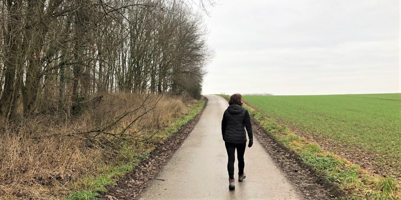 Een vrouw wandelt over een geasfalteerd wandelpad