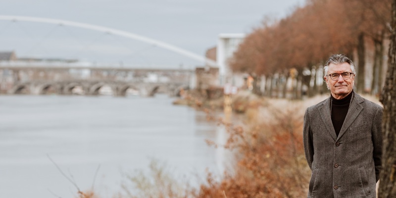 Camille Oostwegel loopt langs de Maas met uitzicht op de bruggen