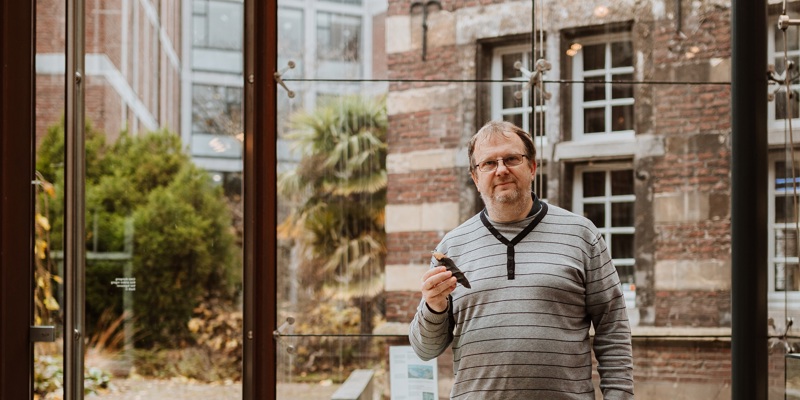 Joep Orbons poseert in een museum met een prehistorische steen in zijn hand
