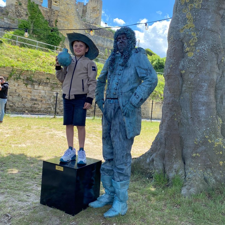 Living Statue van Stadhouder Willen III naast jongen met hoed staande op kubus
