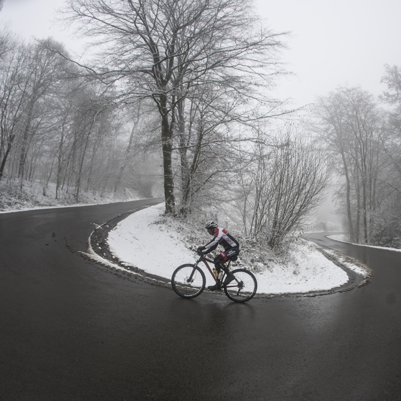 Wielrenner trotseert haarspeldbocht in een besneeuwd landschap