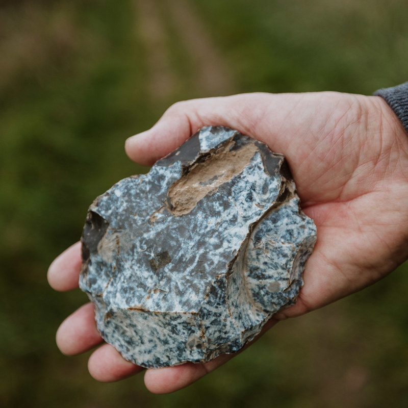 Een hand houdt een stuk vuursteen vast