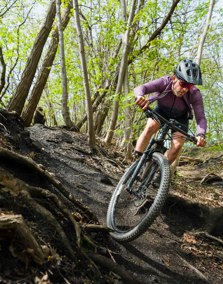 Een mountainbiker maakt een scherpe bocht tussen de wortels van de bomen in het bos