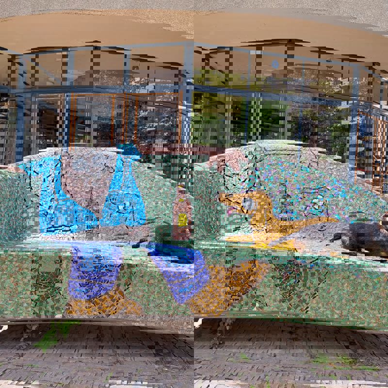 Een hond ligt op een kleurrijk mozaïek bankje 