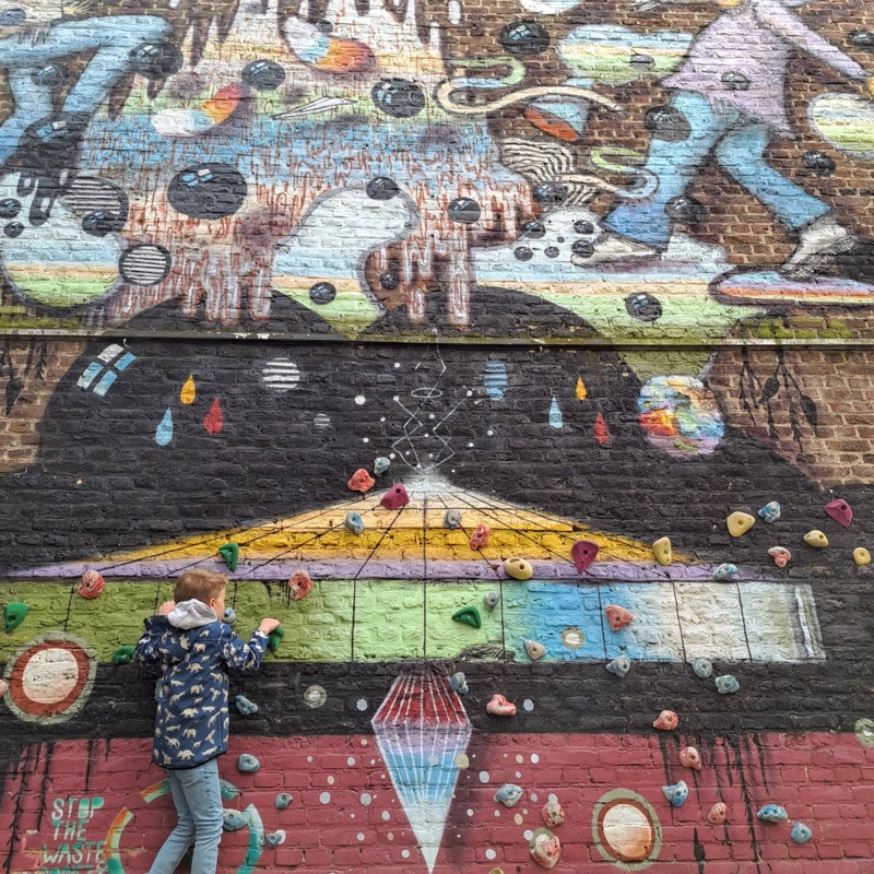 Een kind dat klimt op een muur met een muurschildering 